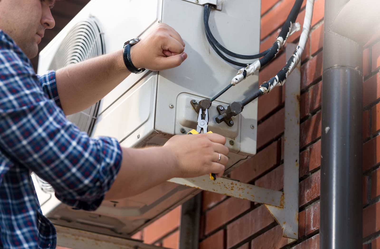 AC technician working on outdoor air conditioning compressor