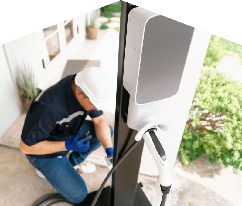 Home service electrician from Mr. Furnace installing an EV charger fixed to a vertical post near a residential entryway.