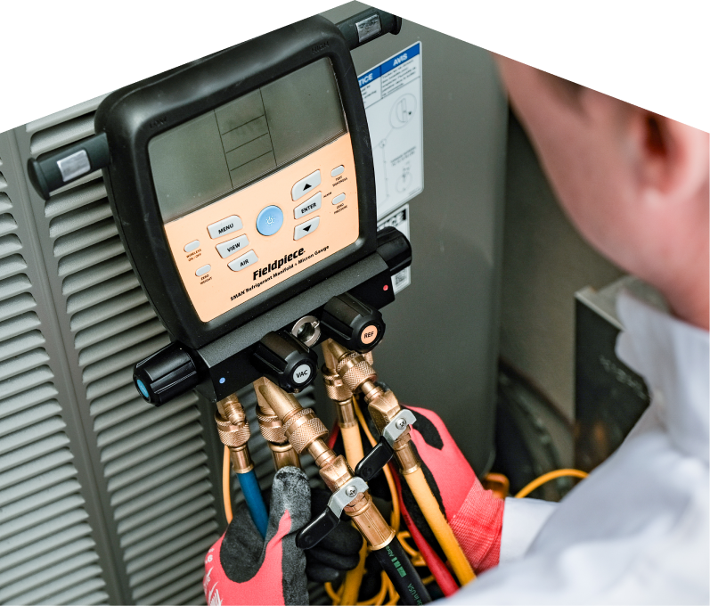 A Mr. Furnace home service crew member uses a digital manifold gauge to check refrigerant levels on an HVAC unit for service. A Mr. Furnace home service crew member uses a digital manifold gauge to check refrigerant levels on an HVAC unit for service.