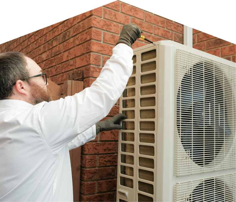 Mr. Furnace HVAC specialist using a screwdriver to complete a heat pump installation beside a brick wall. Mr. Furnace HVAC specialist using a screwdriver to complete a heat pump installation beside a brick wall.